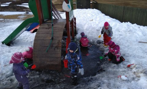 Börnin sækja vatn í pollinn til að selflytja í uppistöðulónið í sandkassanum